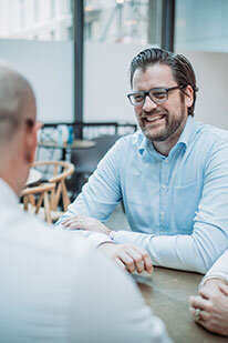 Agile Coach und Trainer Ansgar spricht am Tisch über Agilität | Kraus & Partner