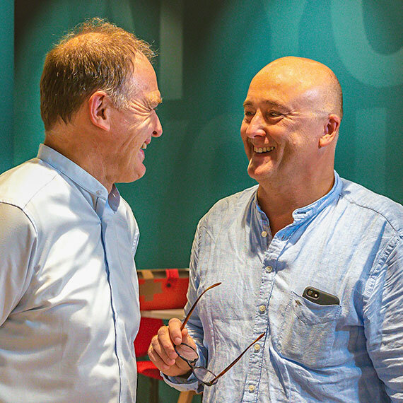 Trainer Stefan Bald im Gespräch mit einer anderen Person - lachend | Kraus & Partner - Transformation Experts