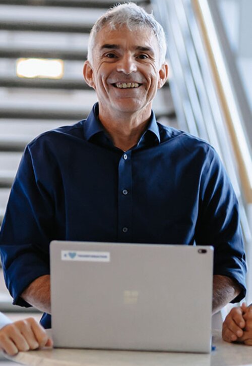 Christian Herlan steht vor Laptop | Kraus & Partner - Transformation Experts